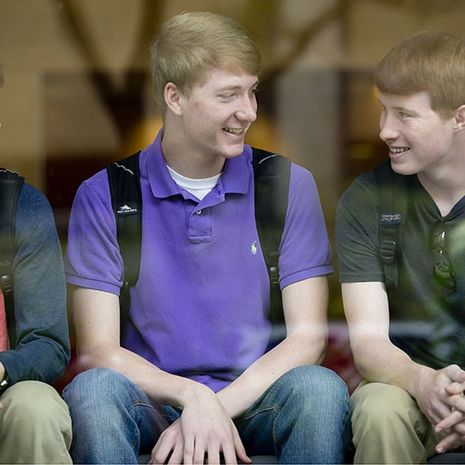 Three young men sitting and talking together. 