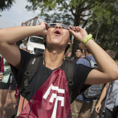 Temple student wearing solar eclipse viewing glasses