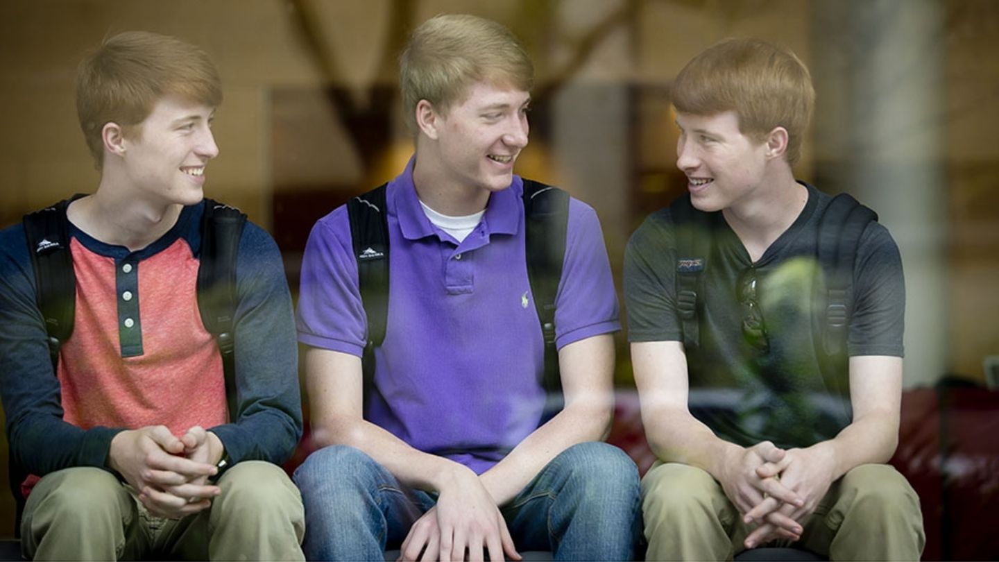The McFerran triplets didn't plan to all attend the same university, but they all independently decided to come to Temple. Three young men sitting and talking together.