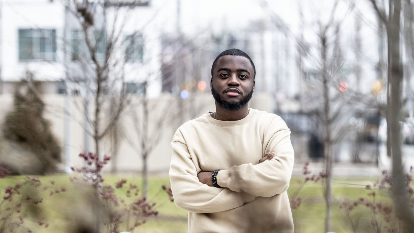 A student in a tan shirt outside in the streets of North Philadelphia.