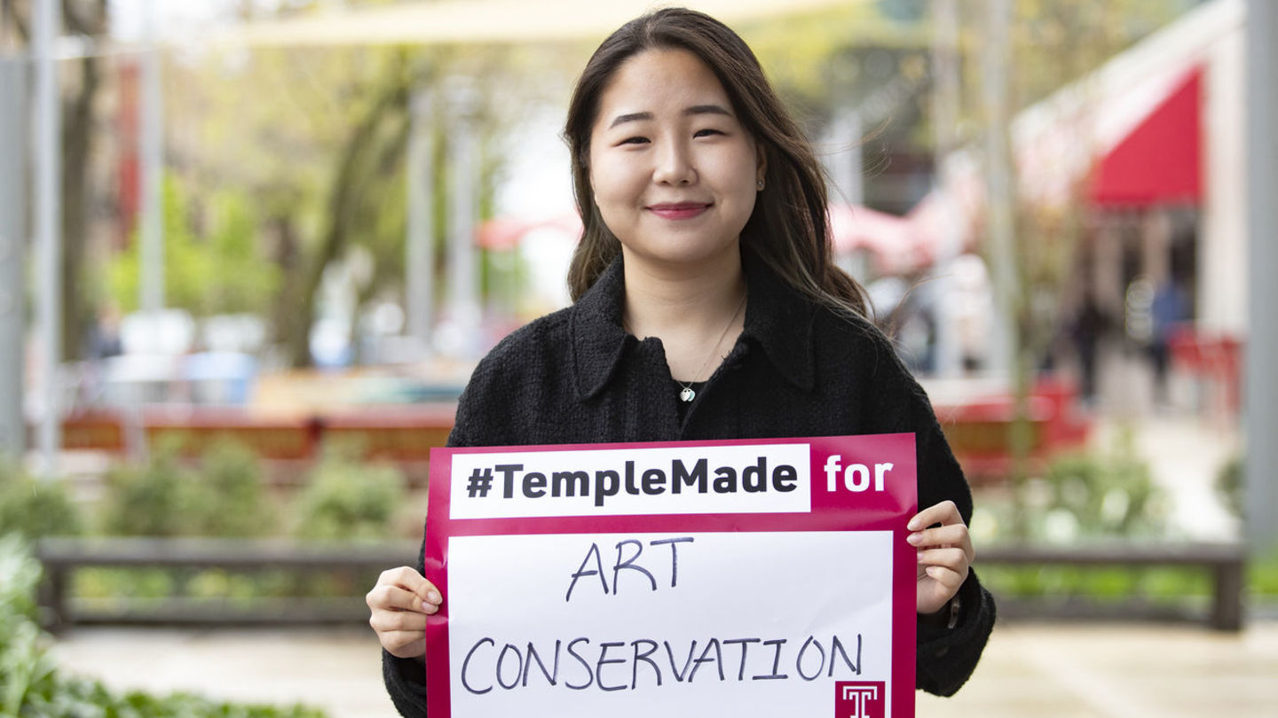 Image of Sera Park holding a sign reading #TempleMade for art conservation.